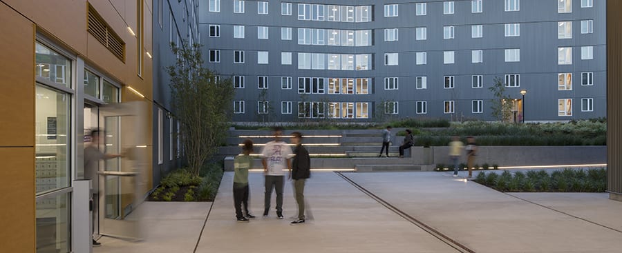 Students conversing in the outdoor covered entryway.