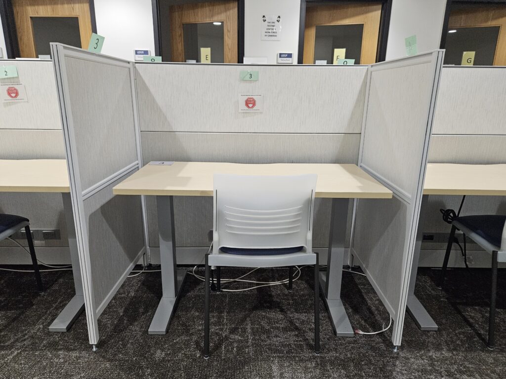 A DRC Testing Cubicle. The desk is surrounded by three cubicle walls for reduced distraction and has a chair.