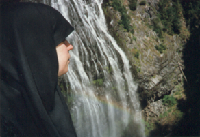 Sarah Safouane in front of a waterfall and rainbow near Reflection Lake at Mount Rainer.