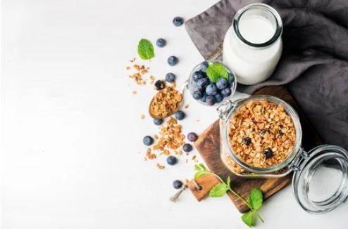 Picture of blueberries, milk and granola with mint and a grey dish towel.