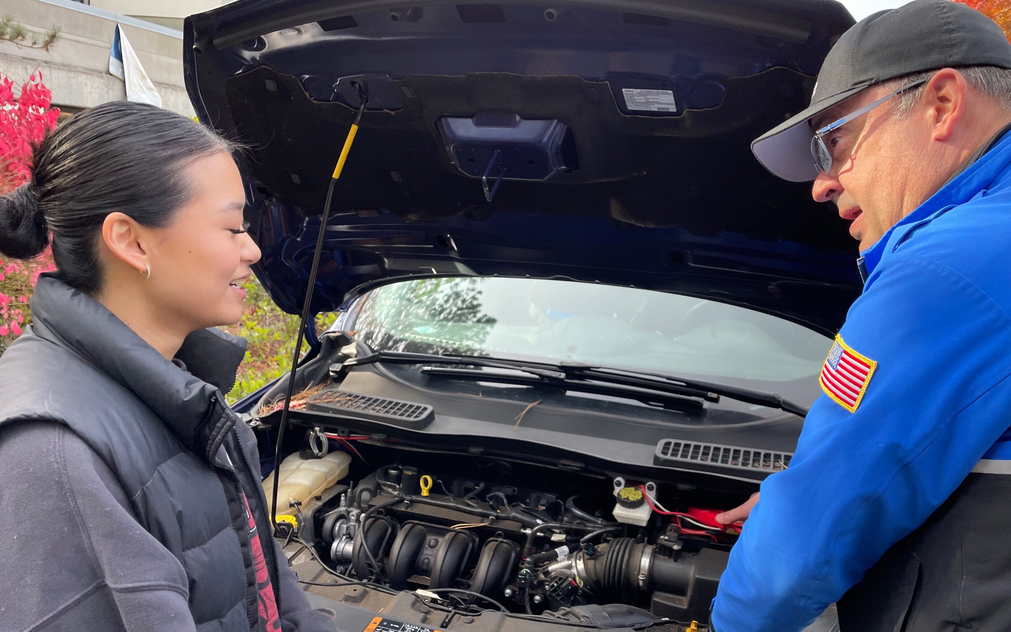 Officer and Student in front of car with open hood