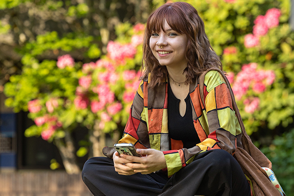 A student smiles while seated outdoors on Bellevue College's campus.