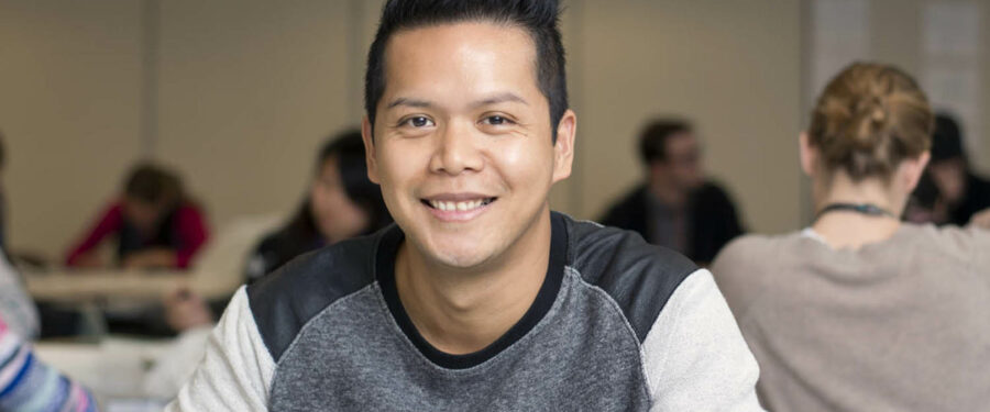 Student smiling in front of a classroom of students in the background