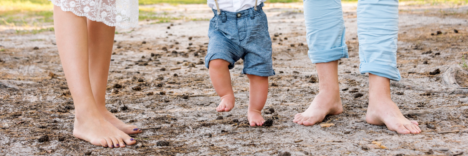 parents and baby with feet in sand