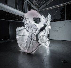 Vow by Mary Coss; 13 wedding gowns cover the metal framework of this 9’ tall pelvic bone with interior illumination.