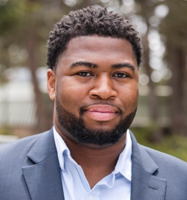 Headshot of Roderick S. Morrison. Esq from the shoulders up smiling in gray coat and white shirt attire.