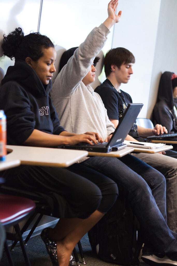 A BC student with their hand raised in a classroom