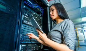 Young engineer businesswoman with tablet in network server room
