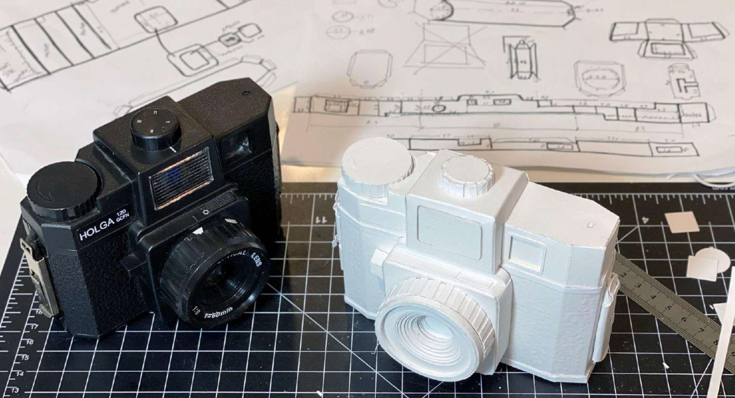 A black and a white camera sitting on grid paper.