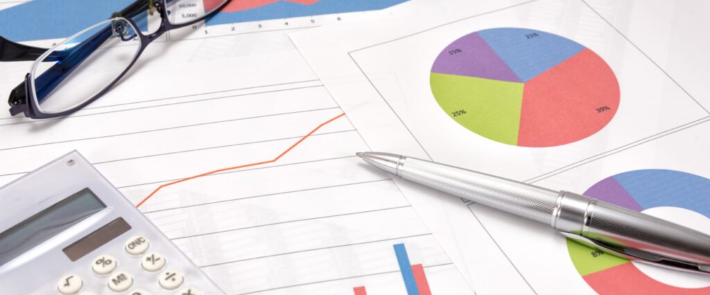 Tools of the accounting trade including pen, calculator, eyeglasses and a ledger sheet