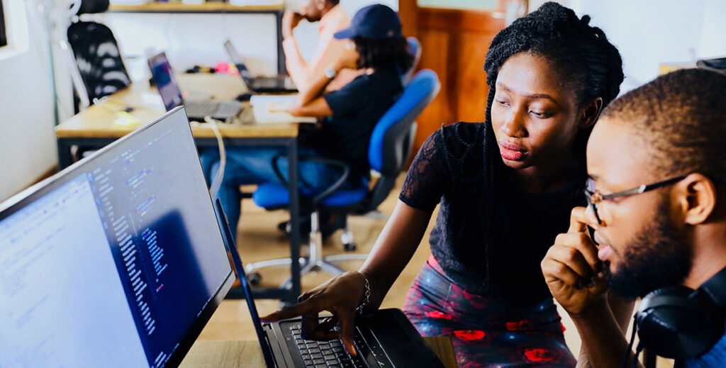 A student and teacher collaborate at a computer.