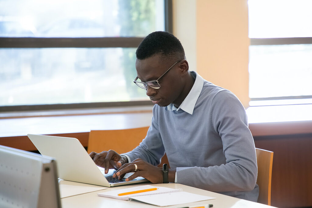 A student works on a laptop by the window.