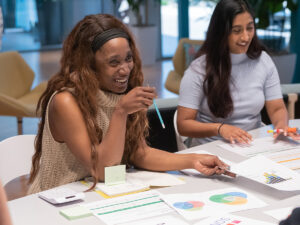 Two business students discuss graphs and reports at a table.