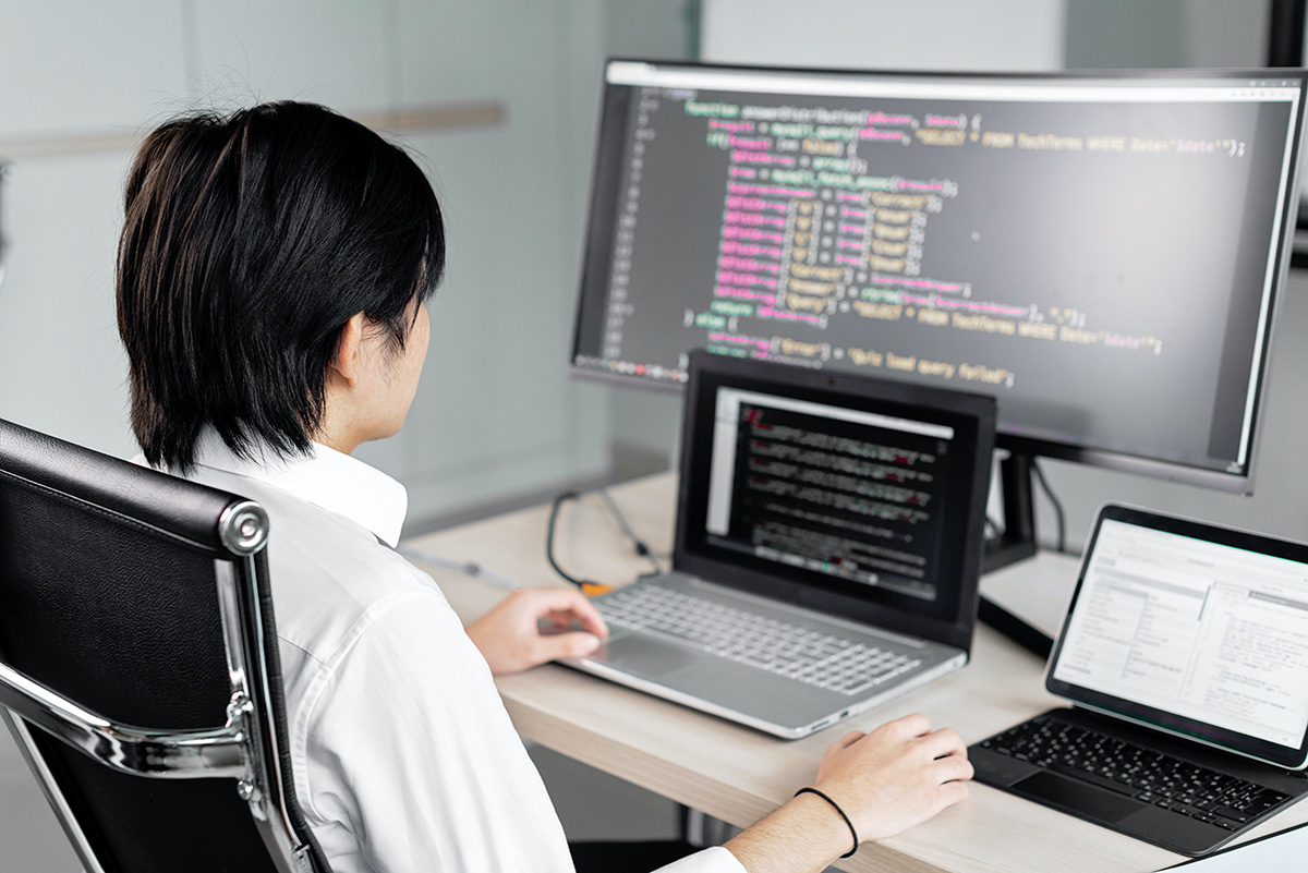 A student works on a coding project on three computers.