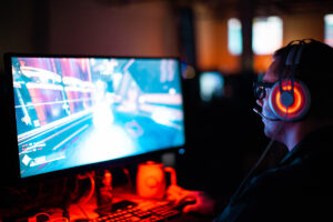 A gamer with headphones looks at the computer screen.