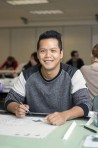 A smiling student works on a drafting project at Bellevue College.