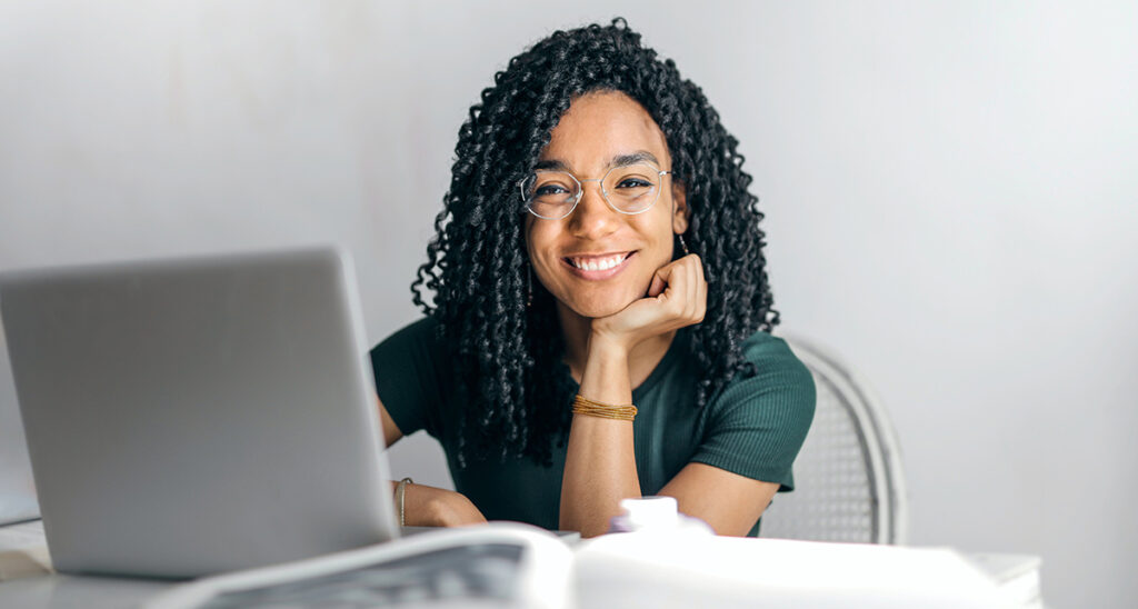 A woman working at a laptop smiles.