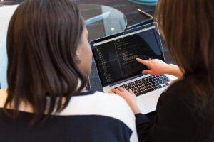 Two people collaborate over code on a laptop.