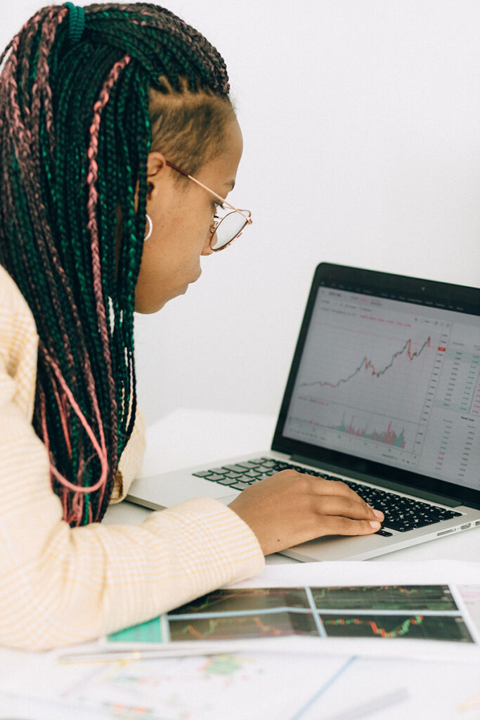 A woman examines data graphs on a laptop.