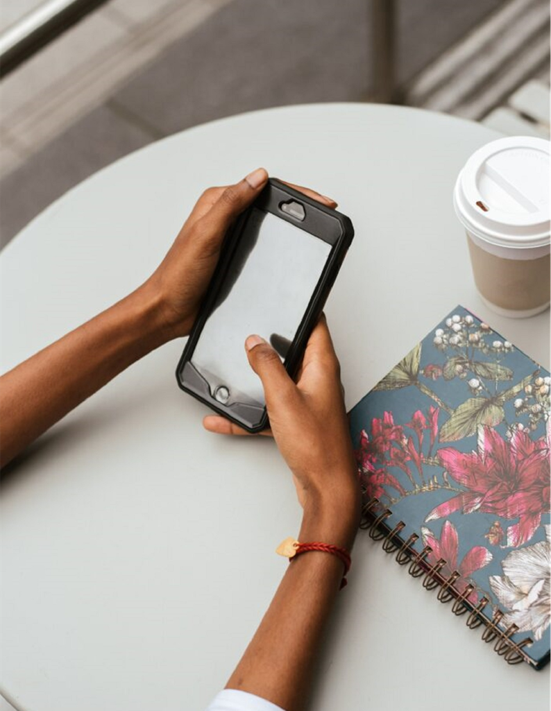 arms resting on a table holding a cell phone