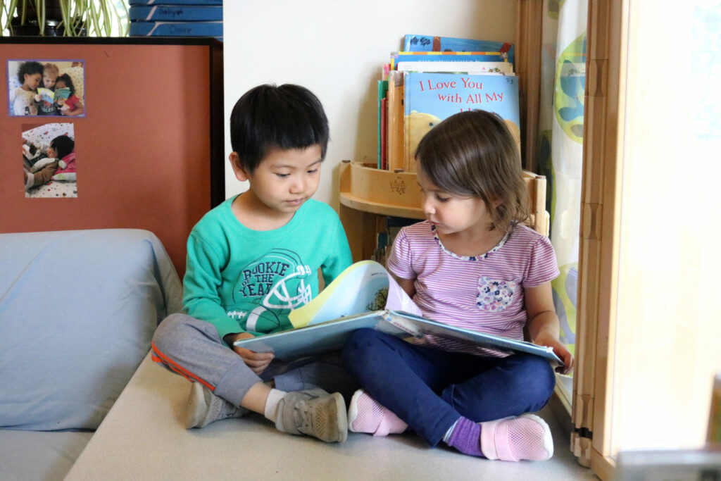 Two preschoolers reading a book together.