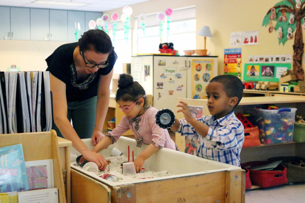 Teacher playing in sand table with children