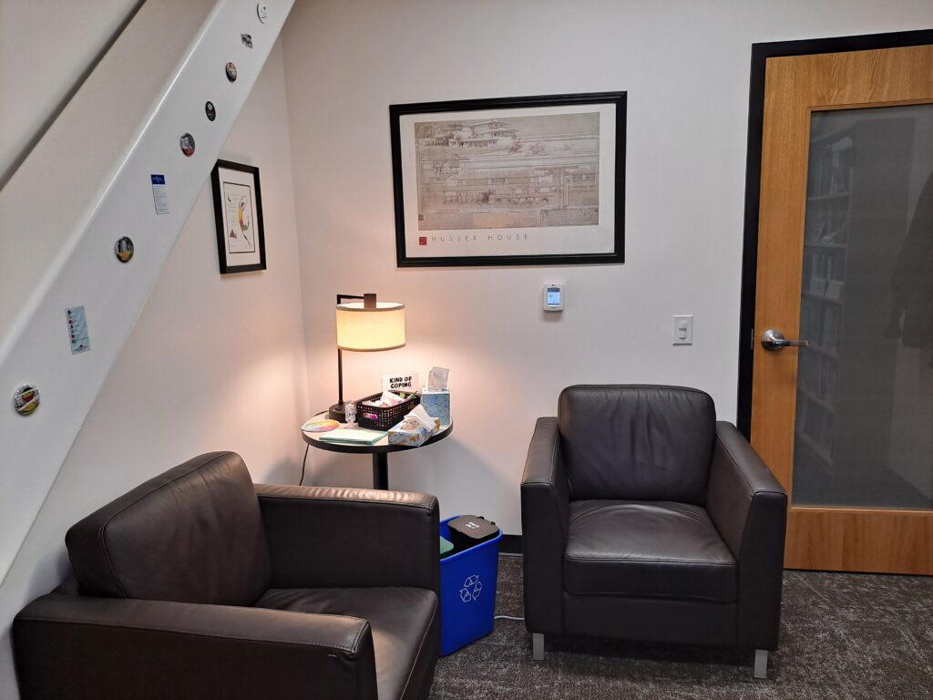 One of the counselors' offices. Image shows two large brown chairs with a table and lamp in between.