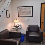 One of the counselors' offices. Image shows two large brown chairs with a table and lamp in between.