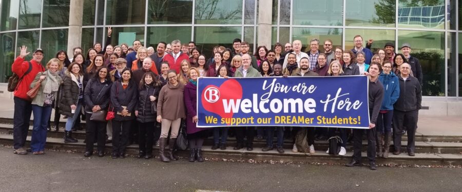 BC Faculty members stand behind a You Are Welcome Here banner