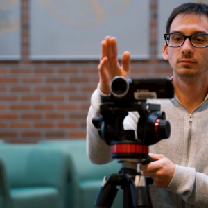 Man behind video camera aligning shot.