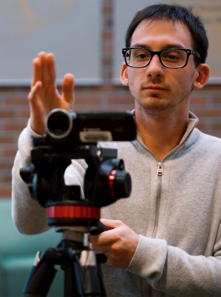 A BC student aligns a shot behind a video camera.