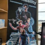 Poster for MXTReality featuring individuals wearing VR headsets and gloves, interacting with augmented and virtual reality elements such as 3D models of buildings, drones, and cruise ships. The poster includes the text "MXTReality," "Augmented Reality," "Virtual Reality," and the website "www.mxtreality.com," along with the MXTReality logo. The background shows Seattle landmarks, including the Space Needle.