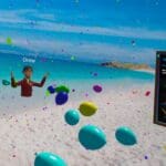 A festive virtual reality beach scene in CurioXR featuring an avatar named “Drew” celebrating with colorful balloons and confetti. To the right, a large welcome sign titled “Welcome to the XR Lab CurioXR Sandbox” provides instructions for VR hand gestures and controls. On the left, a reflective sphere shows a mirrored image of Bellevue College's campus. The vibrant beach background and celebratory visuals create an inviting and playful atmosphere for new users.