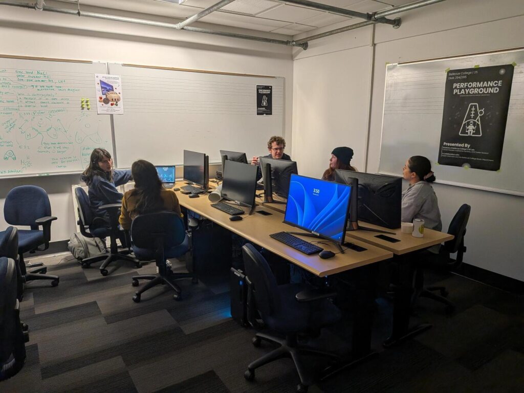 Five students sitting at a table meeting to discuss their 294/DMA 295 project.
