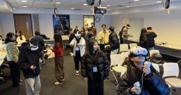 A group of students from South Korea experience XR in a classroom setting and many of them are wearing VR headsets and holding controllers.