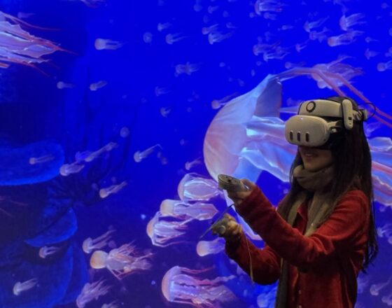 A young woman is immersed in a virtual reality experience featuring an underwater scene filled with glowing jellyfish.